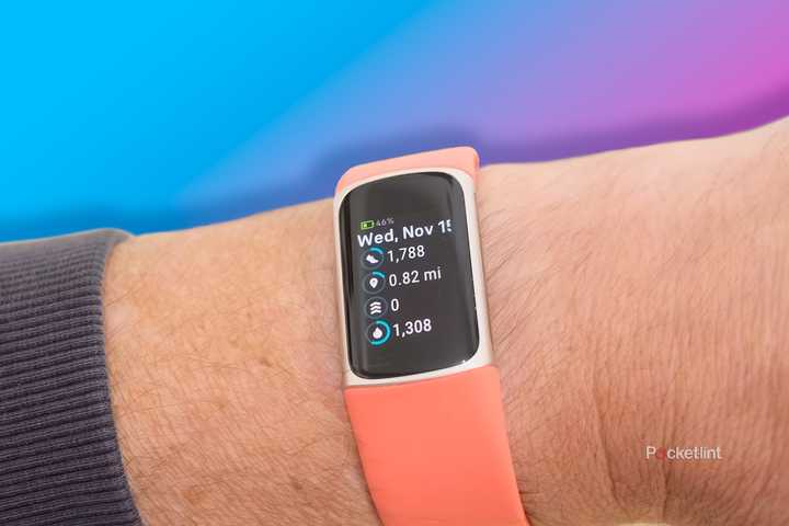The Fitbit Charge 6 on a wrist in front of a purple to pink gradient. 