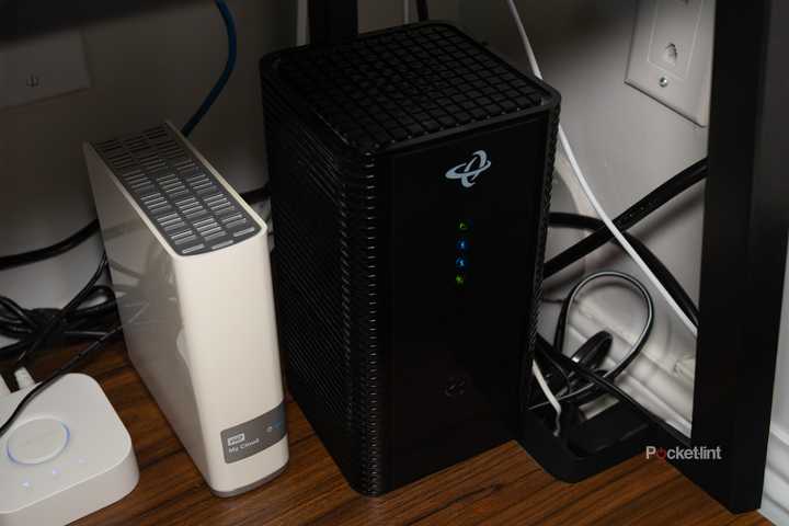 A Wi-Fi router sitting on a shelf next to a backup drive and a Philips Hue Bridge.