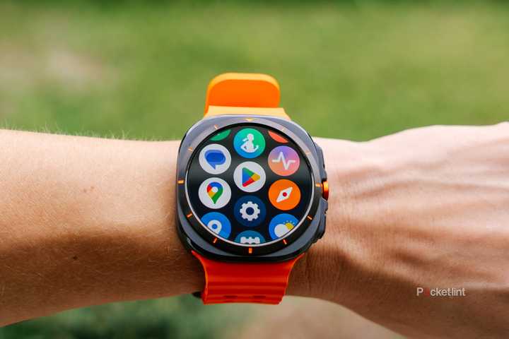 A wrist with the Samsung Galaxy Watch Ultra is held in front of a blurred yard. 