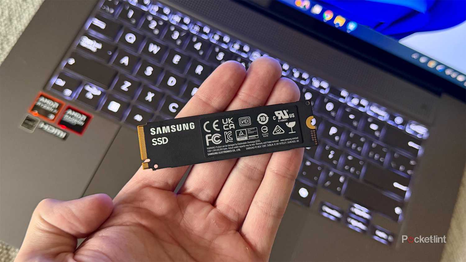 Holding an internal SSD in front of a laptop.